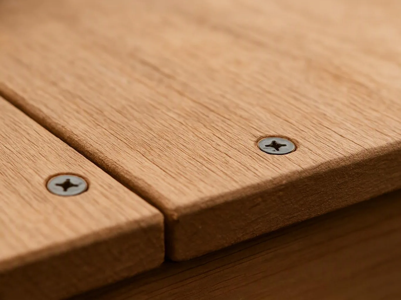 Close-up of two wooden boards joined with visible screws on a warm-toned surface