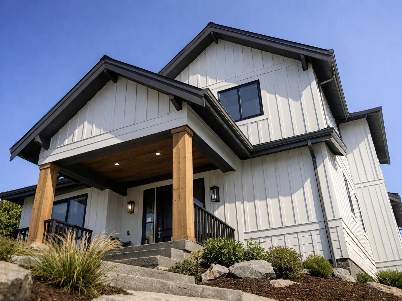 A modern two-story house with white siding, dark trim, and a covered front porch sits under a clear blue sky